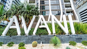 Een groot wit bord met de tekst 'AVANI' voor een modern gebouw met meerdere verdiepingen en balkons.