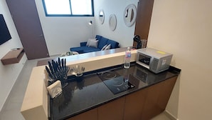 Une cuisine moderne avec un plan de travail noir, un four à micro-ondes et une bouteille d’eau.