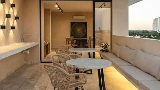 Un balcon extérieur avec un espace salon, une table et des chaises.
