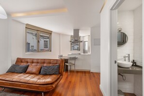 Un soggiorno moderno con un divano in pelle, una zona pranzo e una cucina con piano cottura integrato.
