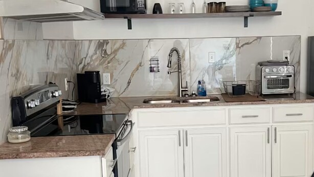 A modern kitchen with white cabinets, a black stove, a microwave, and a toaster.