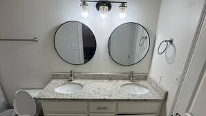 A bathroom with two sinks, a toilet, and a towel ring. - Frenchie Baker (Baker)