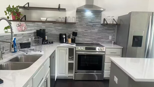 A modern kitchen with a stainless steel range, a built-in oven, and a large refrigerator.