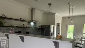 A modern kitchen with a central island, stainless steel appliances, and pendant lighting.
