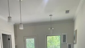 A modern kitchen with a central island, white bar stools, and pendant lighting.