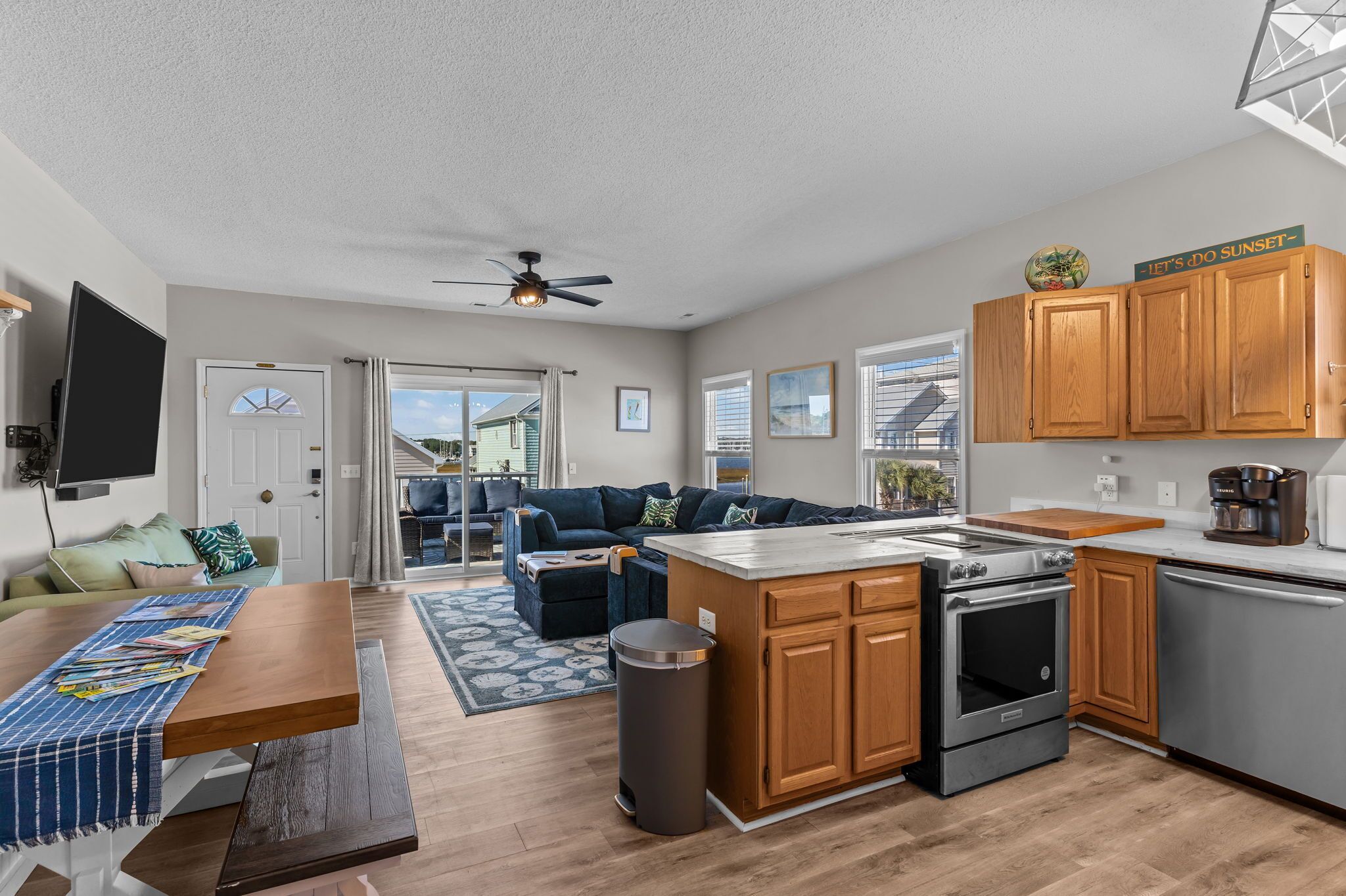 A modern kitchen with wooden cabinets, a central island, and a built-in oven.