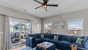 A spacious living room with a sectional sofa, a coffee table, and a ceiling fan. - Top Floor Canal View TownHome - 3 BDRM Sleeps 8 with Linens (Carolina Beach)