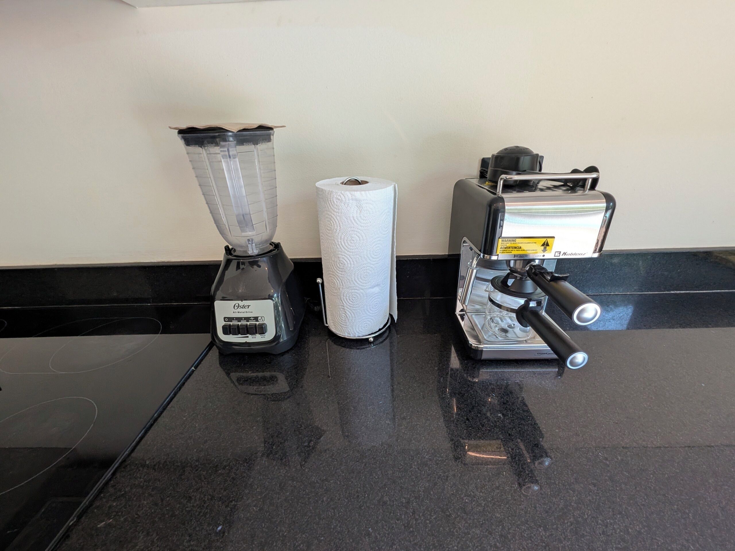 A kitchen counter with a blender, a roll of paper towels, and a coffee machine.