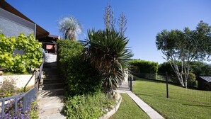Een woonhuis met een stenen trap, een tuin met verschillende planten en een omheind erf.