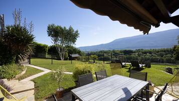 An outdoor patio with a table and chairs, a stone pathway, and a view of a mountainous landscape.