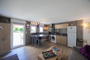 A modern kitchen with a dining area, built-in appliances, and a sliding glass door to the outside. - Gîte le rêve: Between Lake and Mountains, Near Aix-les-Bains and Savoie Grand Revard (Viviers du Lac)