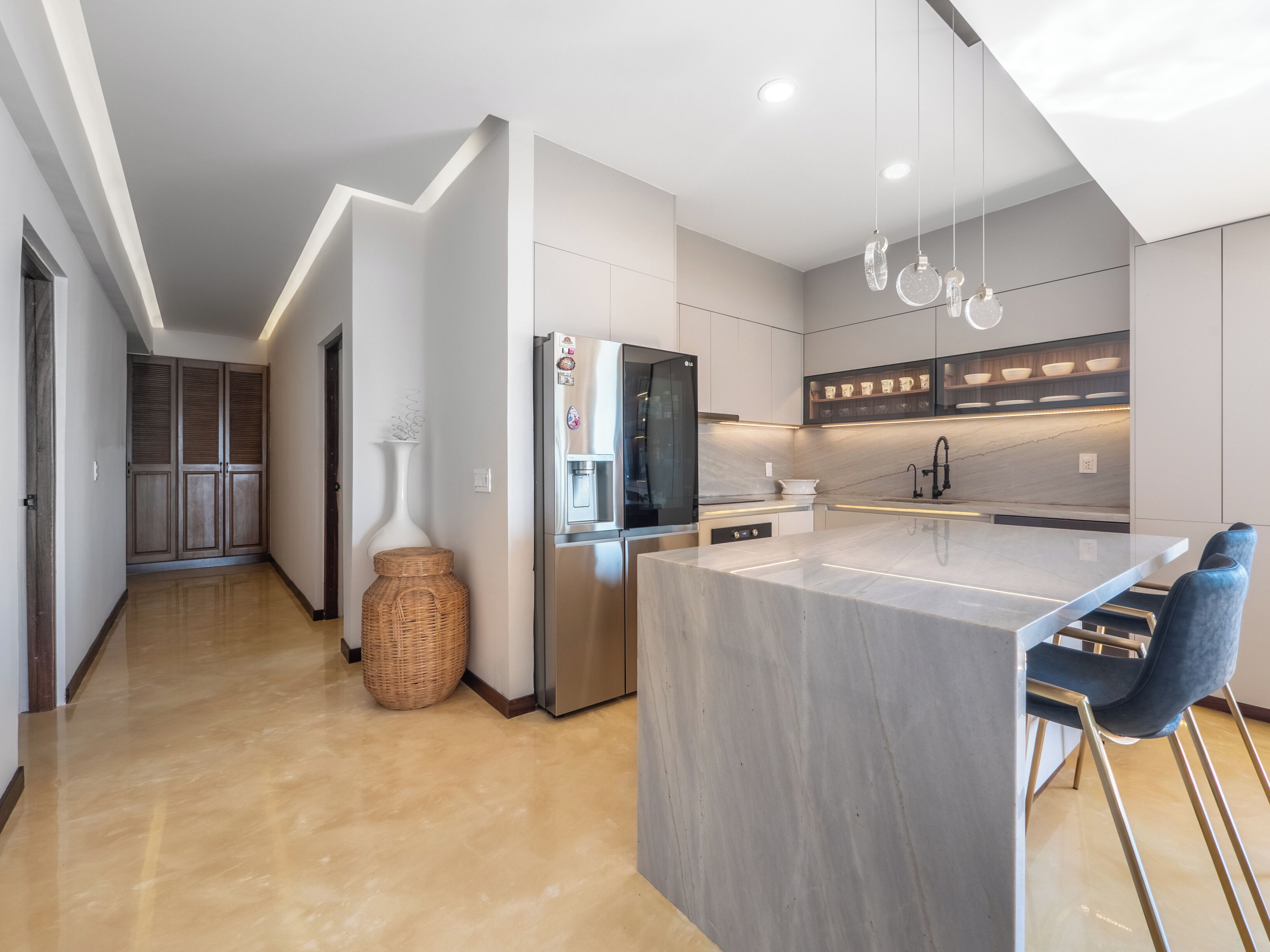 Una cucina moderna con un piano di lavoro in marmo, elettrodomestici in acciaio inossidabile e un'isola integrata con posti a sedere al bancone.