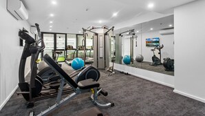 Una gimnàs moderna equipada amb aparells cardiovasculars, màquines de musculació i pilotes d'exercici.