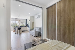 A modern hotel room with a large bed, a sofa, a dining area, and a view through a glass door. - Apartment 'Machadinho' with Private Pool, Wi-Fi and Air Conditioning (Albufeira)
