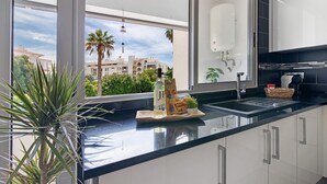 A modern kitchen with a large window, a plant, and a tray with snacks. - Apartment 'Machadinho' with Private Pool, Wi-Fi and Air Conditioning (Albufeira)
