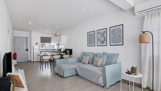A modern living room with a sectional sofa, a dining area, and a kitchen in the background. - Casa machadinho - Albufeira (Albufeira)