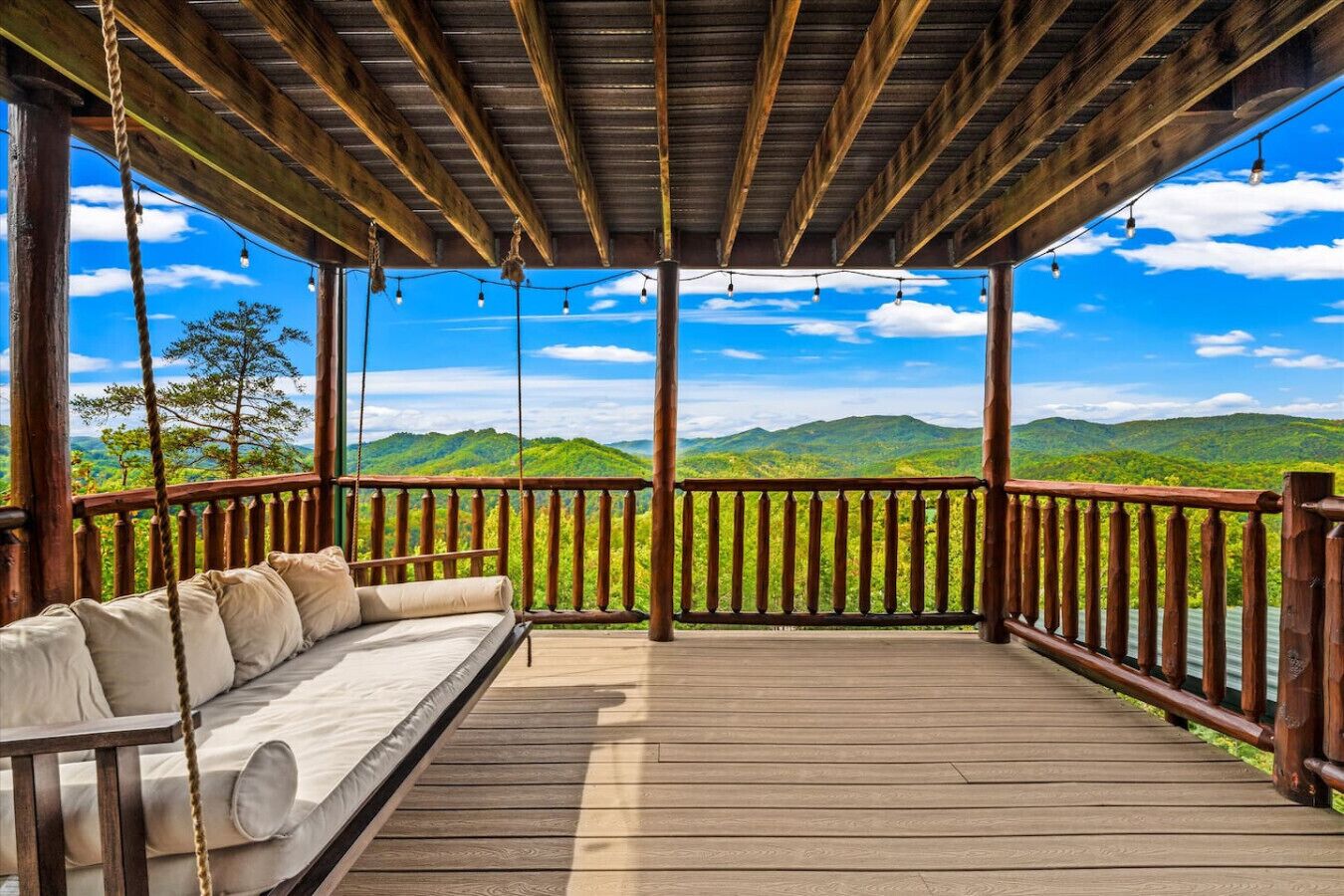 Eine Holzterrasse mit einer Schaukel und Blick auf grüne Hügel.