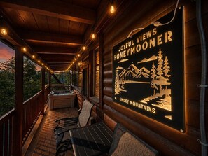 Una terraza de madera acogedora con mobiliario exterior, un jacuzzi y un cartel que anuncia 'Joyful Views Honeymooner' en las Montañas Humeantes.
