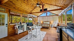 Une cabine spacieuse avec un intérieur en bois, un coin repas, une cuisine et un grand lit.