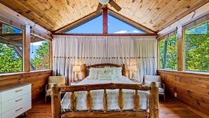 Une chambre dans une cabane en bois, avec un lit, deux tables de chevet et des rideaux.
