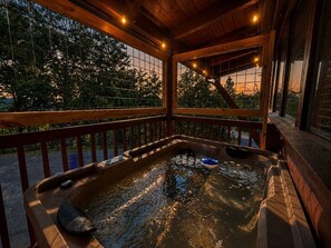 A hot tub with a wooden deck and railing, surrounded by trees. - Romantic Honeymoon Cabin*Peaceful*Community Pool (Pigeon Forge)
