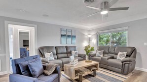 Ein modernes Wohnzimmer mit einem blauen Sofa, zwei braunen Ledercouchs, einem Holztisch und einem gemusterten Teppich.