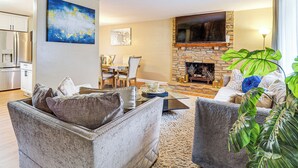 A living room with a stone fireplace, a flat-screen TV, and a dining area with a table and chairs. - 3 Mi to South Park: Quiet Pittsburgh Area Getaway (Pittsburgh)