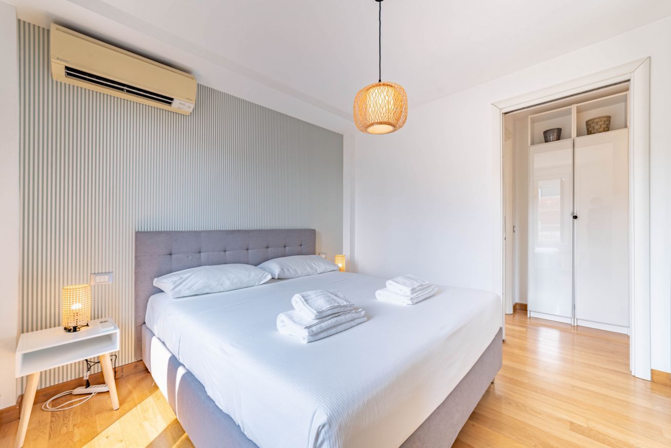 Une chambre à coucher avec un lit, une table de chevet, une lampe et une armoire.