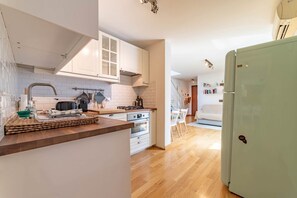 Een moderne keuken met witte kastjes, een houten aanrecht en een groene koelkast.