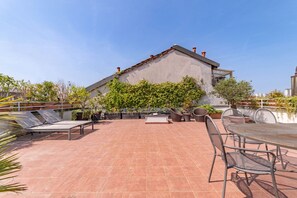 A rooftop patio with a dining table, chairs, and a lounge area. - [10' Navigli] Penthouse with Panoramic View Milan (Milan)
