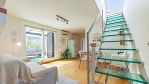 Interior moderno com escada de vidro, área de refeições e uma grande janela.