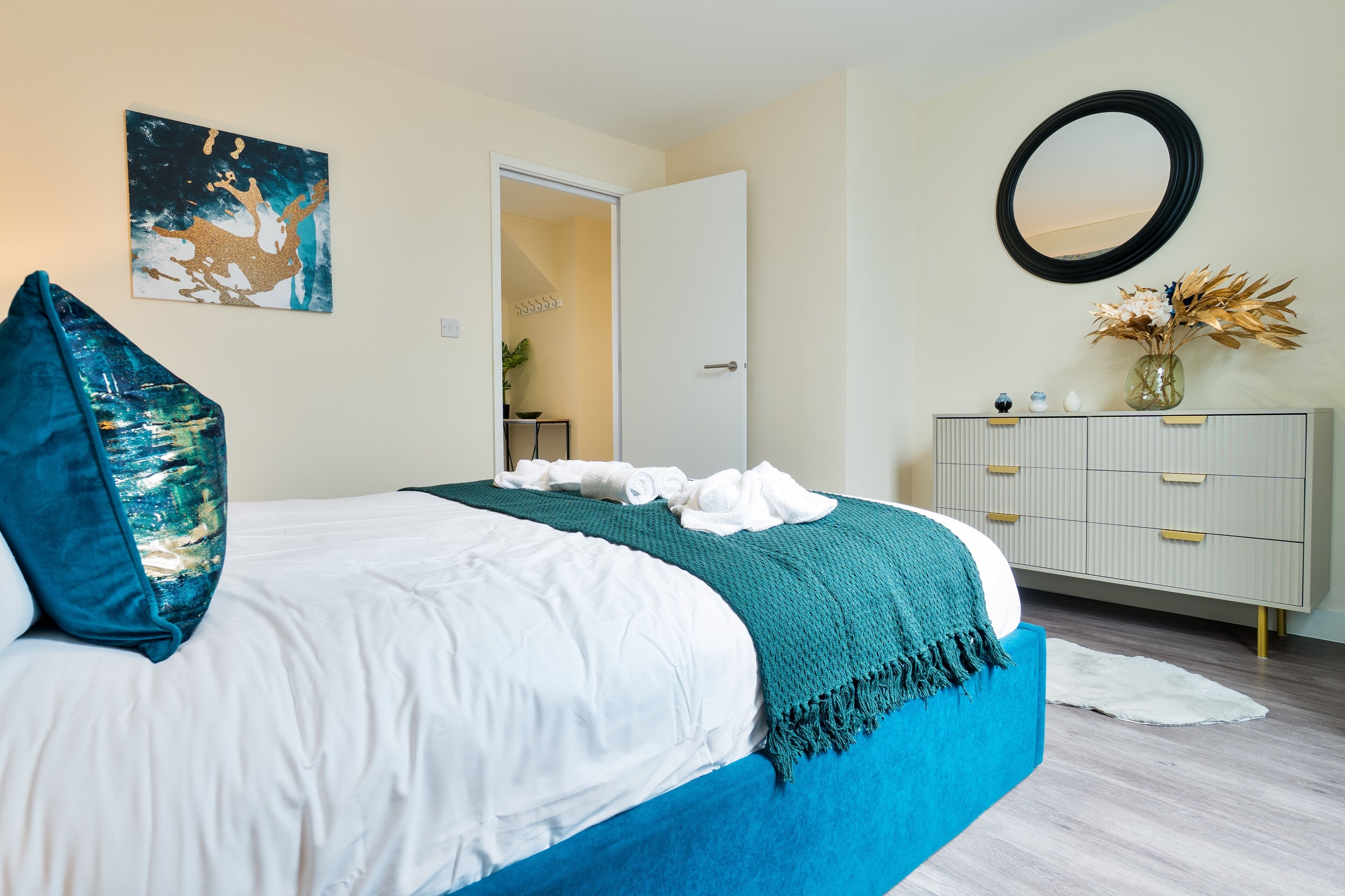 Un dormitorio con cama, cómoda, espejo y un cuadro en la pared.