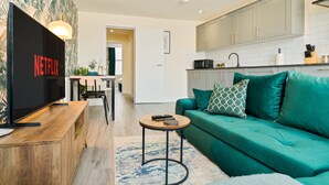 A modern living room with a flat-screen TV, a green sofa, and a wooden coffee table. - Stylish City Centre getaway w/ Cathedral Views (Kent)