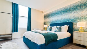 A bedroom with a large bed, a nightstand, a mirror, and a window with curtains. - Stylish City Centre getaway w/ Cathedral Views (Kent)