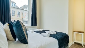 Une chambre d’hôtel avec un lit, des oreillers, une fenêtre et une petite table.
