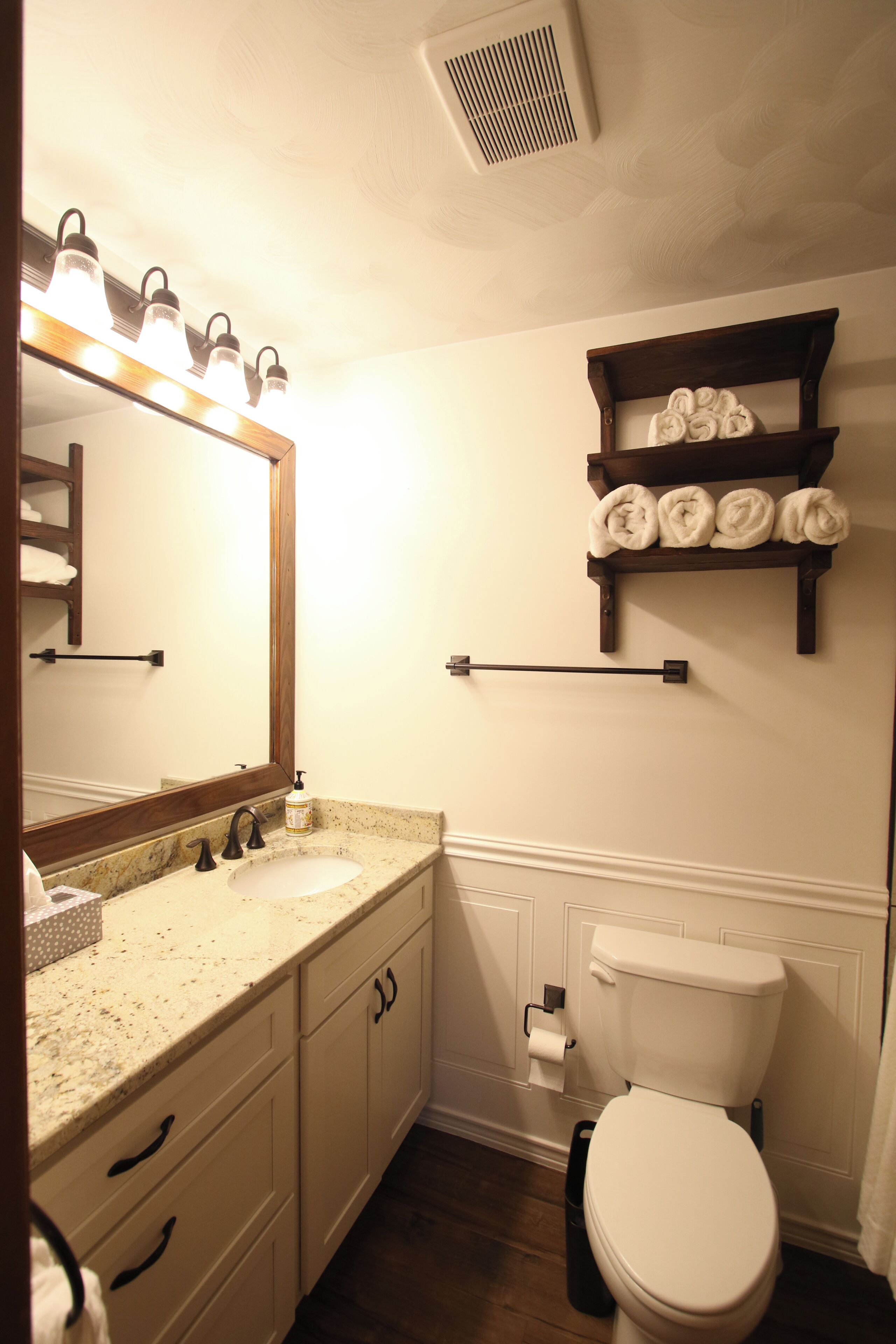A bathroom with a sink, mirror, towel rack, and toilet.