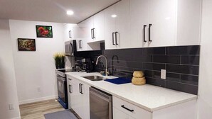 Een moderne keuken met witte kastjes, een zwarte achterwand en een grijze aanrechtblad.
