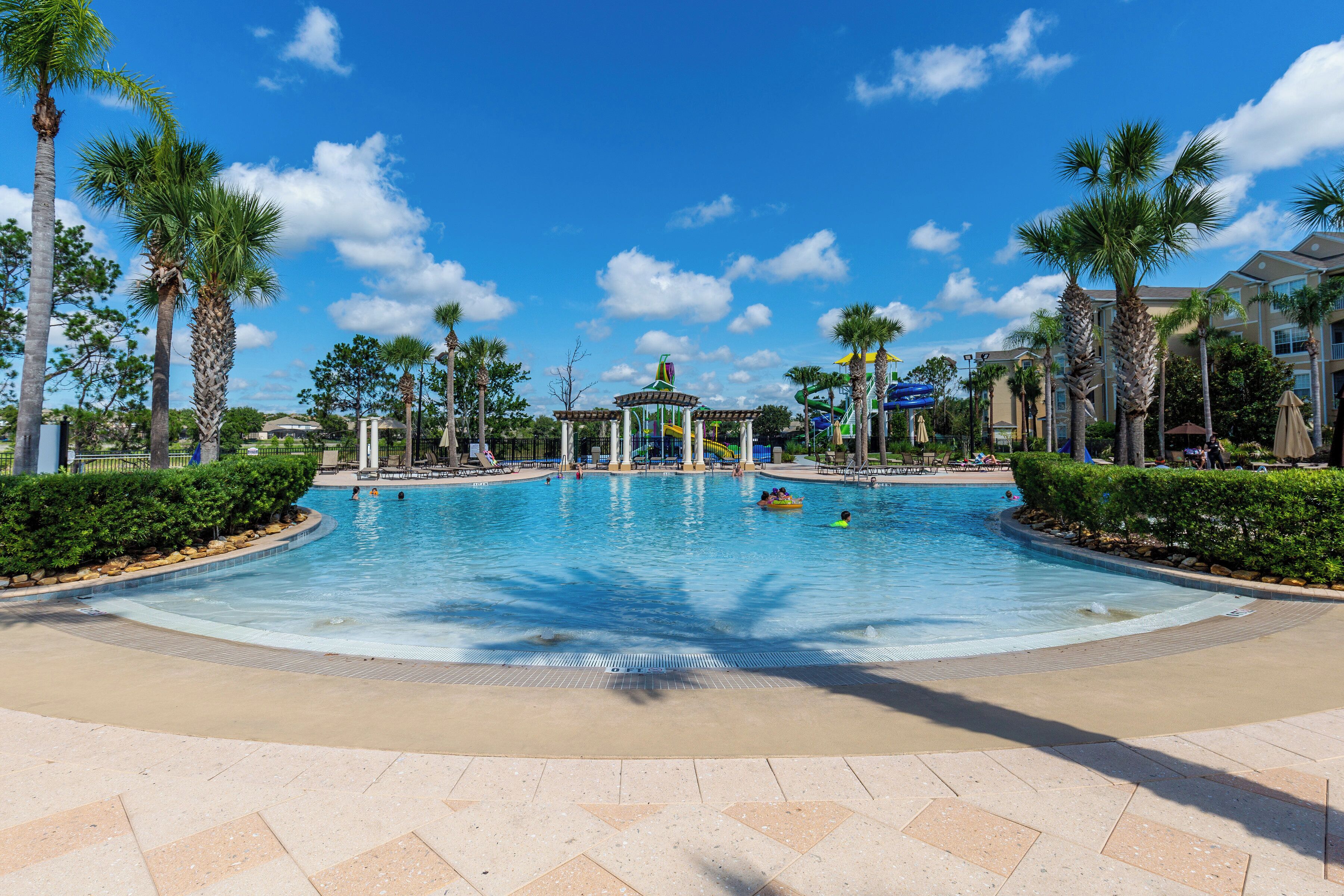 A large outdoor swimming pool with palm trees and a gazebo in the center.