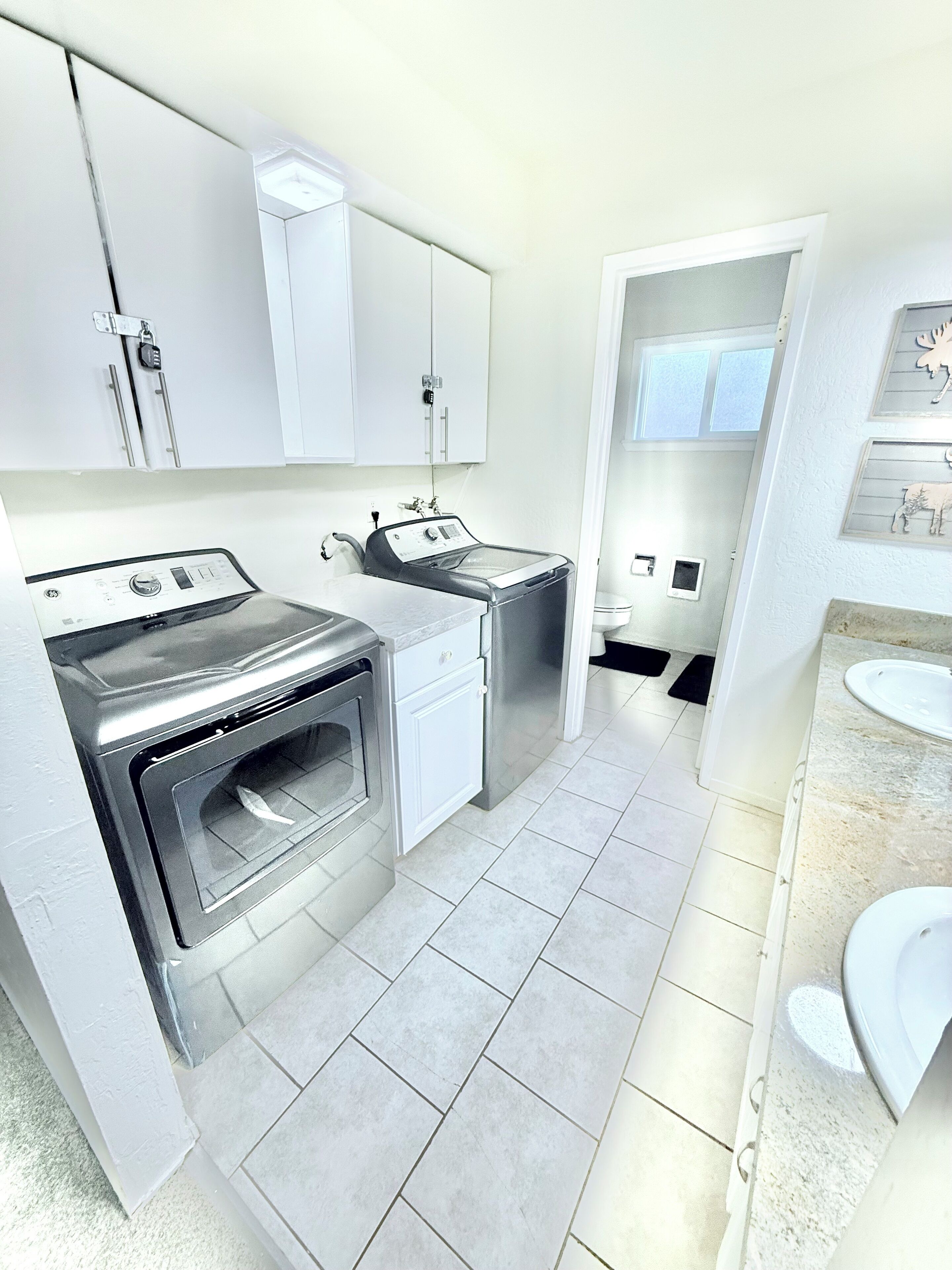 A modern kitchen with stainless steel appliances, white cabinetry, and a tiled floor.