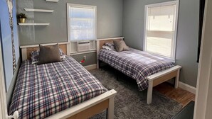 Ein Schlafzimmer mit zwei Betten, einem grauen Teppich und einer Deckenleuchte.