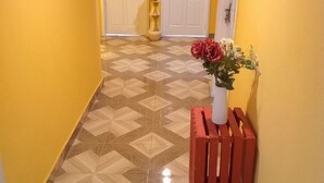 A hallway with patterned flooring, yellow walls, and a red bench with a vase of flowers. - Home Stay In Accra, Travellers With Kids Are Welcomed. 5 mins Walk Away To Beach (Accra)