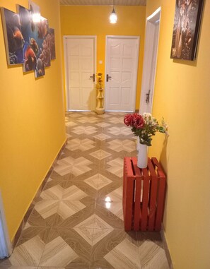 Ein Flur mit einem gemusterten Boden, gelben Wänden und einer roten Bank mit einem Blumenstrauß.