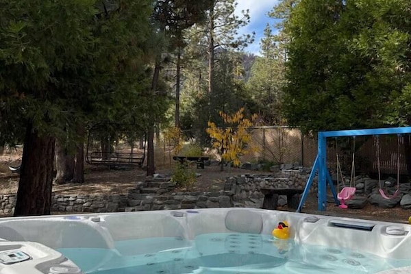 Peaceful outdoor space with a swing set, picnic area, and hot tub.