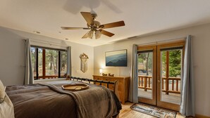 Ein Schlafzimmer mit Bett, Schreibtisch, Stuhl, Deckenventilator und Blick ins Freie.