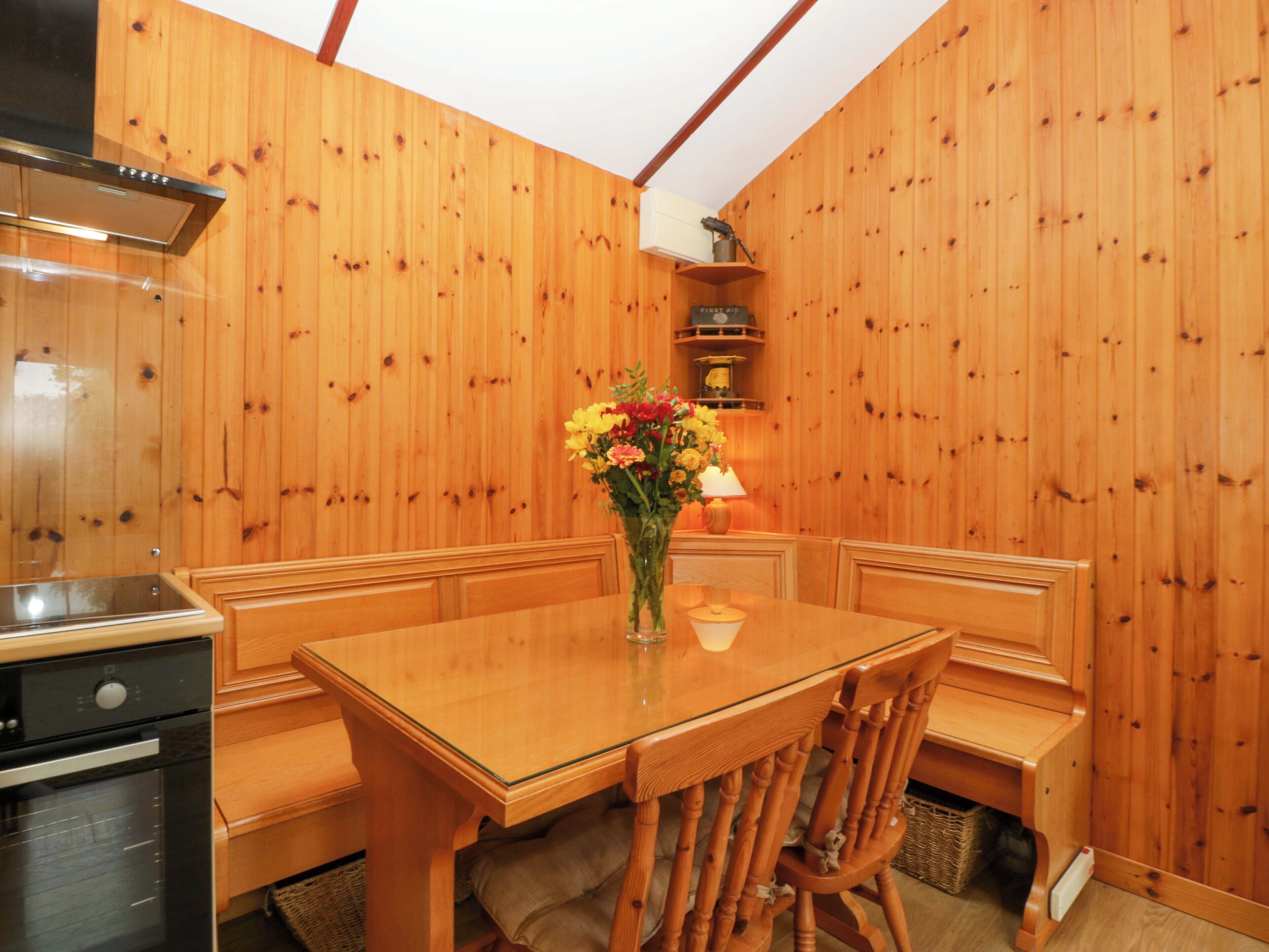 A wooden interior with a dining table, chairs, and a kitchen area.