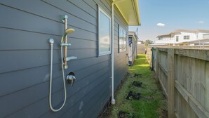 Un barrio residencial con una casa gris, una cerca de madera y una pequeña zona con césped.