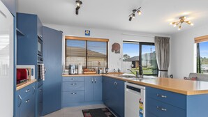 Une cuisine moderne avec des meubles bleus, un plan de travail en bois et un lave-vaisselle.