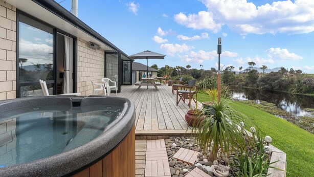 Une maison moderne dotée d’un jacuzzi sur une terrasse en bois, avec vue sur un lac.