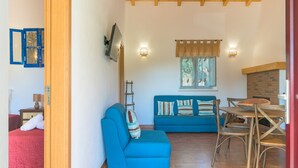 Une pièce avec un canapé bleu, une table à manger avec des chaises, une cheminée et un plafond en bois.
