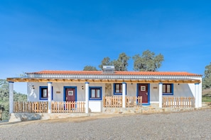 Um edifício de dois andares com telhado de telhas vermelhas, paredes brancas e detalhes em azul.